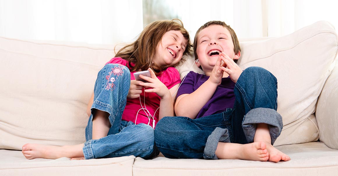 Young Children laughing and enjoying music on sofa